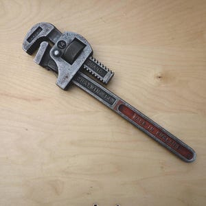 May include: A vintage adjustable pipe wrench, with a grey metal finish and a red handle. The wrench is marked "CHATWIN 14" and "MADE IN ENGLAND". This tool is designed for gripping and turning pipes and other cylindrical objects.