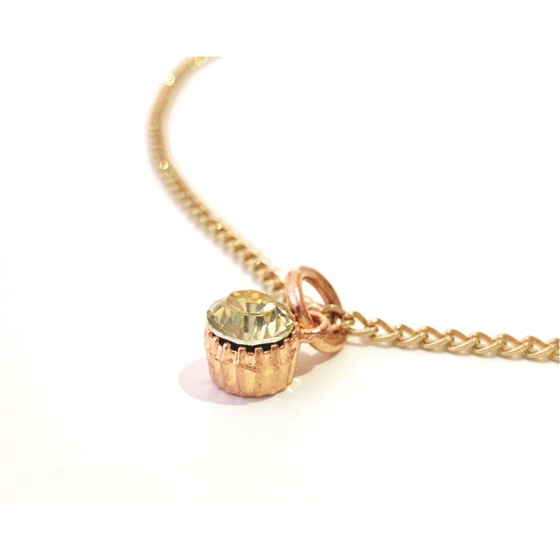 Collar with shiny pendant encrusted with a green stone mounted on a thin gold metal chain
