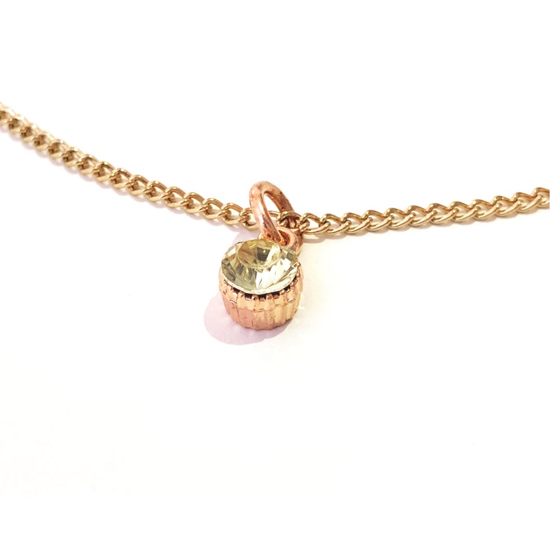 Collar with shiny pendant encrusted with a green stone mounted on a thin gold metal chain
