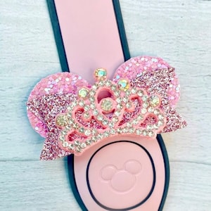 Könnte beinhalten: Rosa glitzernde Minnie Mouse Ohren mit einer funkelnden Strasskrone oben drauf.