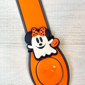 May include: Orange and black Mickey Mouse Halloween themed charm with a ghost Minnie Mouse design. The charm is attached to a black and orange wristband.