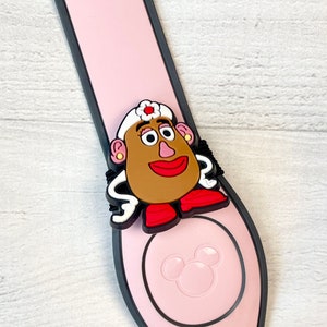 May include: Pink plastic Disney park MagicBand with a black border and a 3D character charm of a female toy character with brown hair, a white hat, and a red and white dress. The character is from the Toy Story franchise.