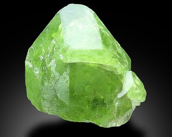 Puede incluir: Un cristal facetado translúcido verde brillante con una punta puntiaguda. El cristal tiene una textura natural y rugosa y es un hermoso ejemplo de una piedra preciosa.
