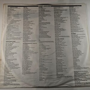 May include: A vintage vinyl record album cover featuring song lyrics and credits. The cover is off-white with black text, showcasing the album's tracklist and artist information. The album is by Lodger and David Bowie.