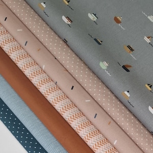 Könnte beinhalten: Eine Auswahl an Stoffmustern mit verschiedenen Mustern und Farben. Designs umfassen Boote auf grauem Hintergrund, weiße Polka Dots, ein braunes Fischgrätmuster und blaue Streifen. Die Stoffe sind in Blau-, Braun- und Rosatönen gehalten.