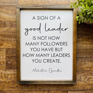May include: A framed sign with a white background and black text that reads "A sign of a good leader is not how many followers you have but how many leaders you create. Mahatma Gandhi".