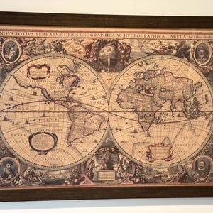 May include: A framed vintage world map print in a brown wooden frame. The map is in a classic style with detailed lines and text. The title of the map is "NOVA TOTIVS TERRARVM ORBIS GEOGRAPHICA AC HYDROGRAPHICA TABVLA."