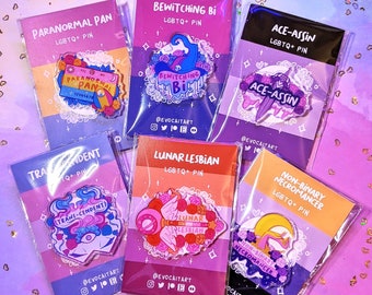 May include: Six colorful enamel pins with LGBTQ+ themes. The pins are packaged in clear plastic bags with a white background and feature a variety of designs, including a witch, a moon, a sword, and a cassette tape. The pins are all labeled with the text "LGBTQ+ Pin".