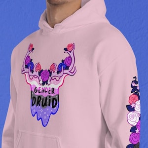 May include: Pink hoodie with a graphic of a deer head with flowers and the text "Gender Druid" in a bi-pride color scheme. The sleeves have a floral design with bi-pride colors.