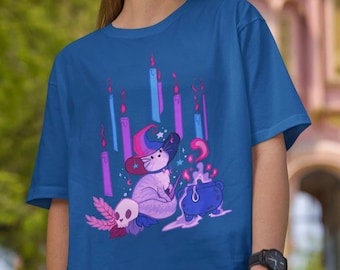 Può includere: Una maglietta blu con una grafica di un gatto che indossa un cappello da strega e tiene una bacchetta magica. Il gatto è circondato da candele e un calderone. La grafica è in stile cartone animato.