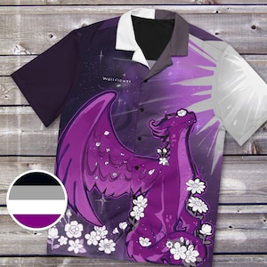 May include: Purple button-up shirt with a fantasy dragon design. The dragon is purple with white flowers and wings, set against a starry purple and white background. The shirt has short sleeves and a white collar. The word "Wallflower" is printed on the shirt.
