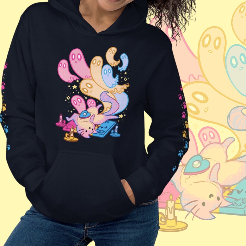 Peut inclure: Un sweat-shirt &agrave; capuche noir avec une illustration color&eacute;e d'un chat entour&eacute; de fant&ocirc;mes. Le chat porte un chapeau bleu et tient un instrument de musique. Le sweat-shirt a une poche sur le devant et une capuche &agrave; cordon.