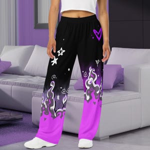 May include: Black and purple wide-leg pants with a flame design and white graphic details. The pants have a drawstring waistband and a relaxed fit.