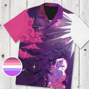 May include: Short-sleeved button-up shirt with a fantasy-themed design. The shirt features a purple and pink celestial background with bats, clouds, and a figure surrounded by roses. The text "Cold Blooded" is visible.