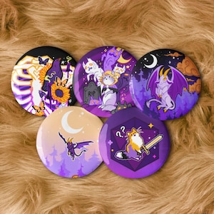 May include: Five circular buttons with fantasy and Halloween designs. The illustrations include a skeleton with a raven, cats with ghosts, a dragon, and a fox with a sword. The buttons feature purple, black, orange, and yellow colours.
