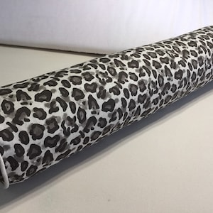 Cuscino in cotone marrone con stampa leopardata; cuscino rotondo con cordoncino a contrasto con motivo animalier; cuscino cilindrico con motivo leopardato e cordoncino