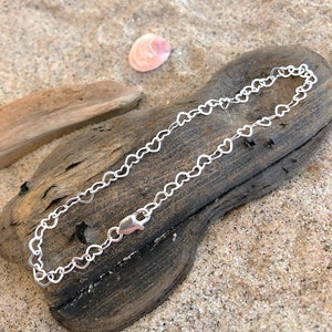 Könnte beinhalten: Ein silbernes Armband mit einer herzförmigen Kette und einem Karabinerverschluss.