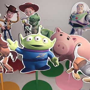 May include: A set of colorful cardboard cutouts of popular characters from the Toy Story franchise, including Woody, Buzz Lightyear, Jessie, Rex, and Alien. The cutouts are attached to sticks and can be used as party decorations.