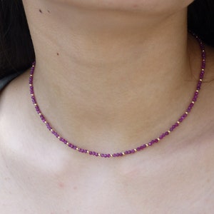 Op de afbeelding: Een delicate gouden ketting met kleine paarse edelsteen kralen.