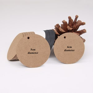 May include: Two round brown paper gift tags with holes for string. The larger tag is 5 cm in diameter and the smaller tag is 4 cm in diameter.