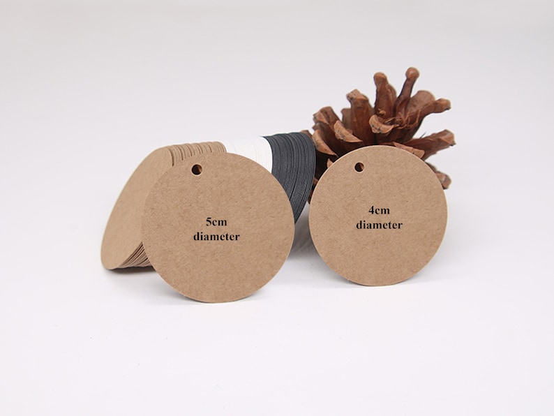 May include: Two round brown paper gift tags with holes for string. The larger tag is 5 cm in diameter and the smaller tag is 4 cm in diameter.