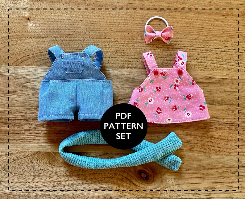 K&ouml;nnte beinhalten: Ein PDF-Schnittmuster-Set zum N&auml;hen von Puppenkleidung. Das Set enth&auml;lt Schnittmuster f&uuml;r eine Latzhose, ein Kleid und ein Stirnband. Die Latzhose ist aus blauem Denim, das Kleid ist rosa mit wei&szlig;em und rotem Blumendruck und das Stirnband ist rosa mit einer Schleife.