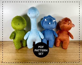 May include: Four plush dinosaur toys in green, light blue, blue, and orange. The toys are standing on a wooden surface. The text "PDF PATTERN SET" is in a black circle.