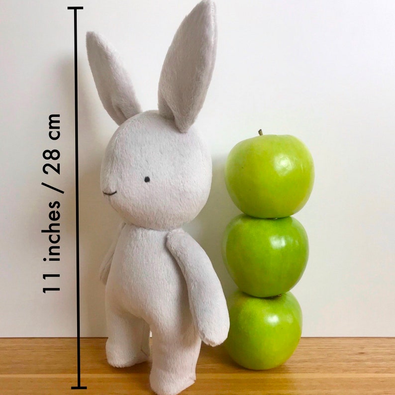 May include: A grey plush bunny rabbit toy standing 28 cm tall, next to a stack of three green apples.