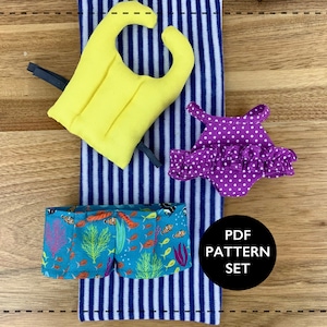 May include: A PDF pattern set for sewing a swimsuit, a life vest, and swim trunks. The swimsuit is purple with white polka dots and a ruffle trim. The life vest is yellow. The swim trunks are teal with a colorful fish and coral print. The text "PDF PATTERN SET" is on a black circle.