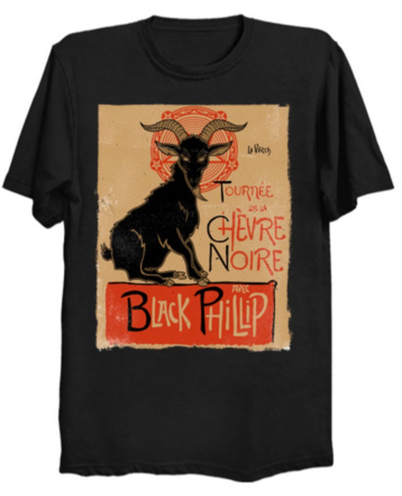 May include: Black t-shirt featuring a vintage-style graphic of a black goat with large horns. The design includes the text "Tourn&eacute;e de la Ch&egrave;vre Noire" and "Black Phillip" in red and black lettering.