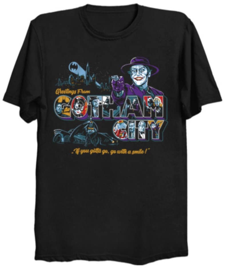 May include: Black t-shirt featuring a colorful graphic of Gotham City with the Joker and Batman. The design includes the text "Greetings From Gotham City" and the quote "If you gotta go, go with a smile!"