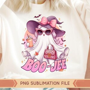 May include: A pink and white ghost wearing a witch hat and sunglasses, holding a pink purse and a pink and white iced coffee. The ghost is surrounded by pink and white stars and the text "BOO-JEE".