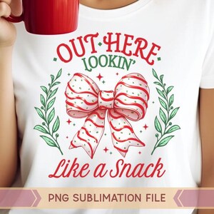 May include: White t-shirt with a red and white striped bow and green leaves. The text "Out Here Lookin' Like a Snack" is printed on the shirt. PNG Sublimation File.
