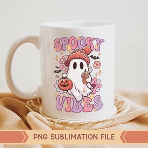 May include: White ceramic mug with a pink and purple design featuring a ghost holding a pumpkin and a cup of coffee. The text "Spooky Vibes" is written in pink and purple letters.