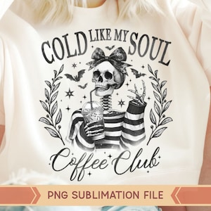 May include: A white sweatshirt with a black and white graphic design of a skeleton holding a cup of coffee. The text on the graphic says "Cold Like My Soul Coffee Club".