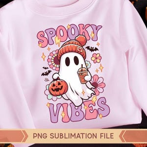 May include: A pink long-sleeved shirt with a sublimation design of a cartoon ghost wearing a beanie and holding a pumpkin and a cup. The text "Spooky Vibes" is in a retro font.