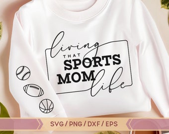 May include: White sweatshirt with the text "Living that Sports Mom Life" in black lettering. The text is inside a black rectangle. There are three black and white sports icons on the sleeves: a baseball, a football, and a basketball.