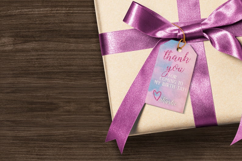 Peut inclure: Une bo&icirc;te cadeau envelopp&eacute;e de papier brun avec un ruban rose et une &eacute;tiquette qui dit "merci d'&ecirc;tre venu &agrave; mon anniversaire ! Karlie".