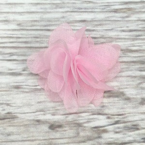 May include: A single pink fabric flower with a ruffled texture. The flower is made of soft, sheer material and has a delicate, feminine look.