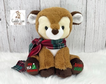 May include: A plush brown deer stuffed animal wearing a red and green plaid scarf. The left foot features the text "My 1st Christmas" with a small green tree graphic, and the right foot features the text "Liam 2026" in red and green lettering.