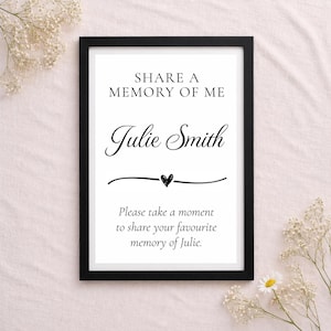 May include: A black framed sign with white background and black text that reads: SHARE A MEMORY OF ME, Julie Smith, followed by a decorative line with a small heart, and the text: Please take a moment to share your favourite memory of Julie.