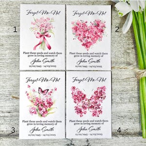 May include: Four white seed packets with forget-me-not flower designs. Each packet has the text "Forget-Me-Not" and a different floral design. The text "Plant these seeds and watch them grow in loving memory of John Smith 12/02/1945 - 14/03/2025" is printed on each packet.