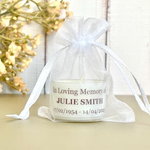 May include: A white tea light candle in a clear glass container with a white organza bag. The candle has a label that reads "In Loving Memory of JULIE SMITH 17/02/1954 - 14/04/2025".