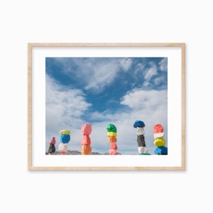Puede incluir: Una fila de esculturas de rocas coloridas contra un cielo azul con nubes blancas. Las rocas están pintadas en varios colores, incluyendo rosa, amarillo, verde, azul y blanco.