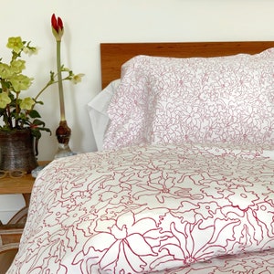 May include: White bedding with a red floral pattern. The bedding is made of a soft, comfortable fabric and features a delicate floral design.