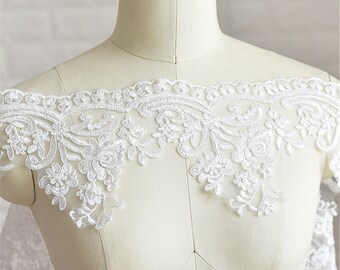 May include: White lace trim featuring a delicate floral design. The trim has a scalloped edge and is ideal for adding a touch of elegance to any project.