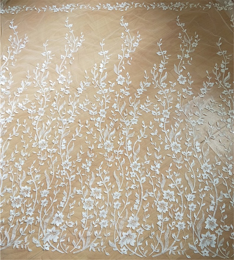 Puede incluir: Tela de encaje floral blanca con un delicado patr&oacute;n de flores y hojas sobre un fondo transparente.