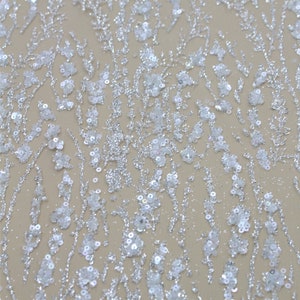 以下が含まれることがあります： 白と銀のラメ生地で、花柄です。生地の裏地はメッシュになっています。