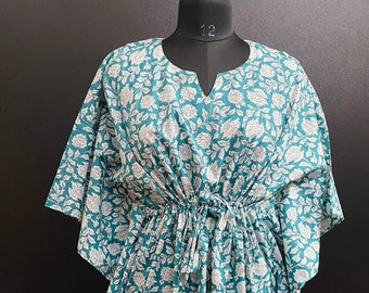 May include: A teal blue kaftan with a white floral print. The kaftan has a V-neck and a drawstring waist. The fabric is soft and flowy.