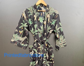 Könnte beinhalten: Eine schwarze und grüne, langärmelige Robe mit einem Dschungel-Druck, der Zebras, Leoparden und Palmen zeigt. Die Robe hat einen Bindegürtel und Seitentaschen.